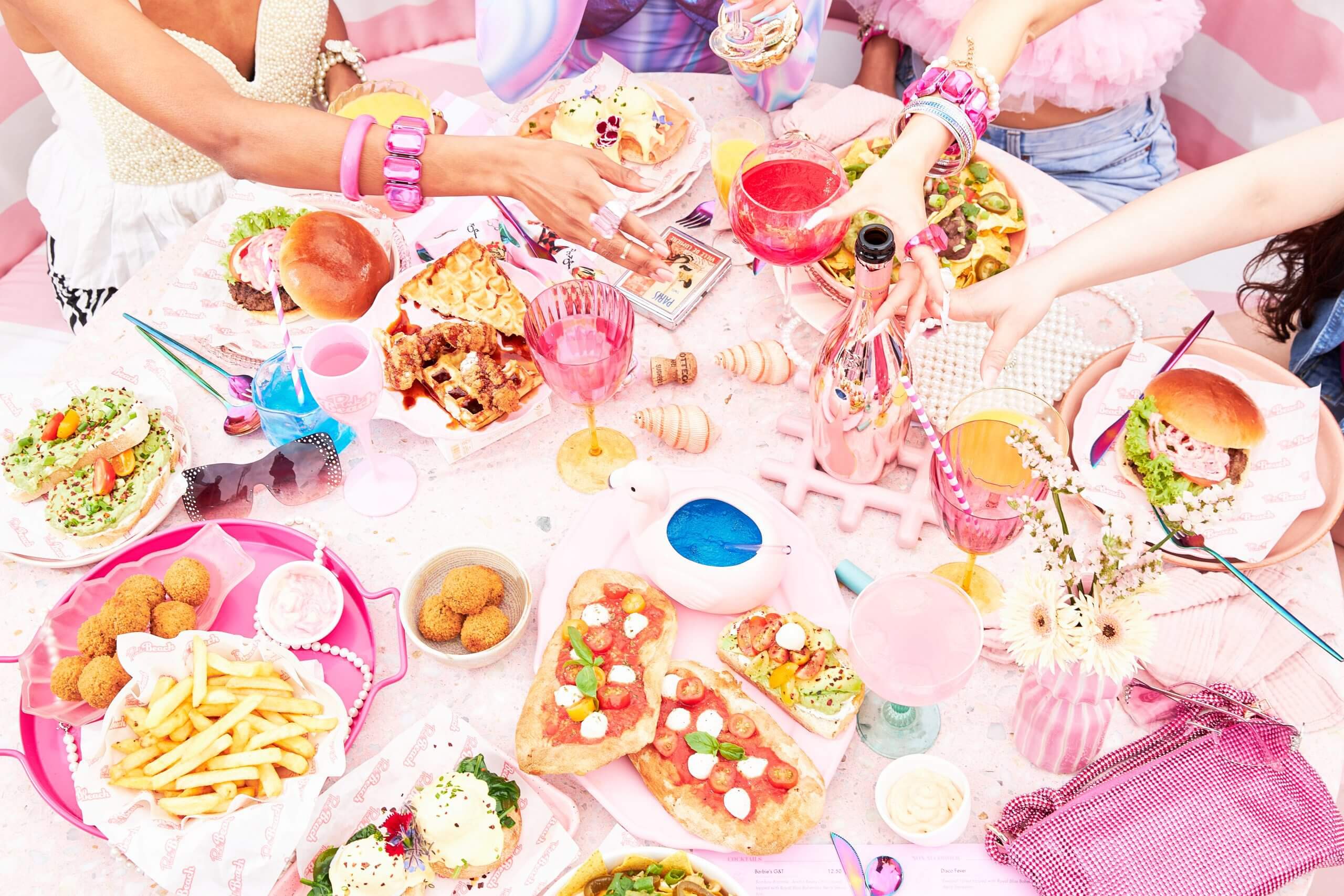 Veel kleurrijk eten en drinken op een tafel tijdens de Pink Beach brunch